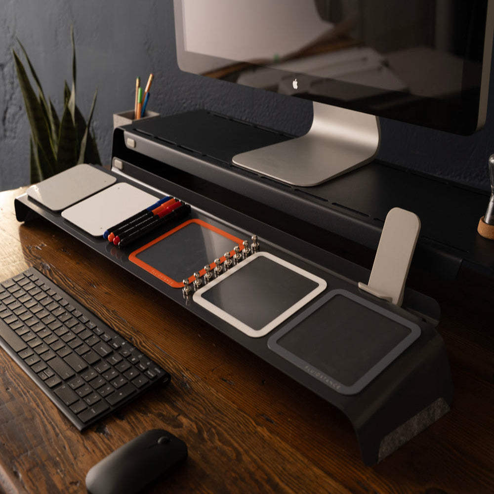 FluidStance Dry Erase Board with a monitor riser, keyboard storage, and ergonomic setup on a wooden desk.