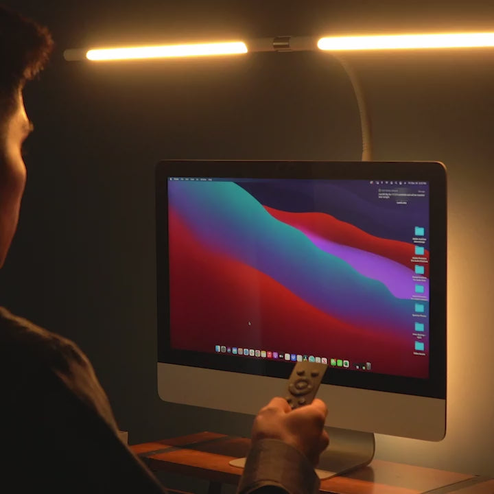 Man adjusting white desk light with remote control